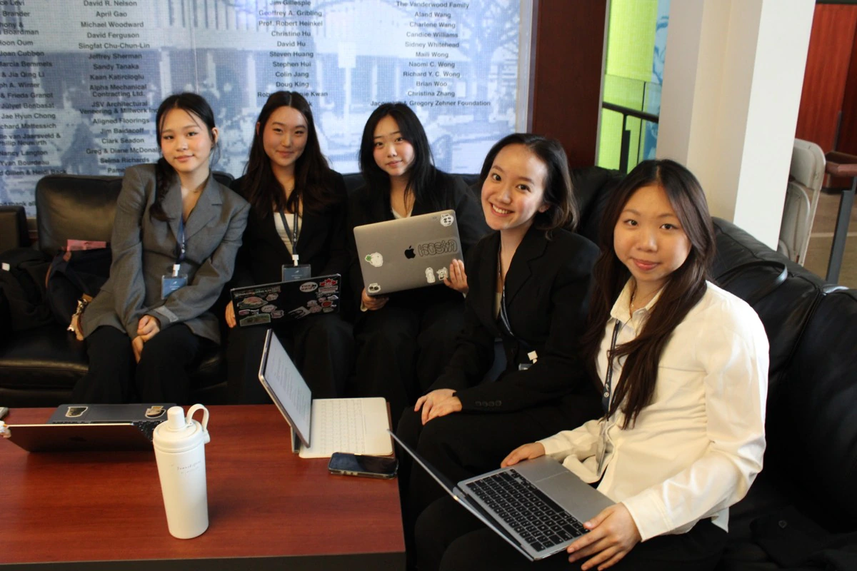 Five Momentum participants seated together with laptops in a campus lounge