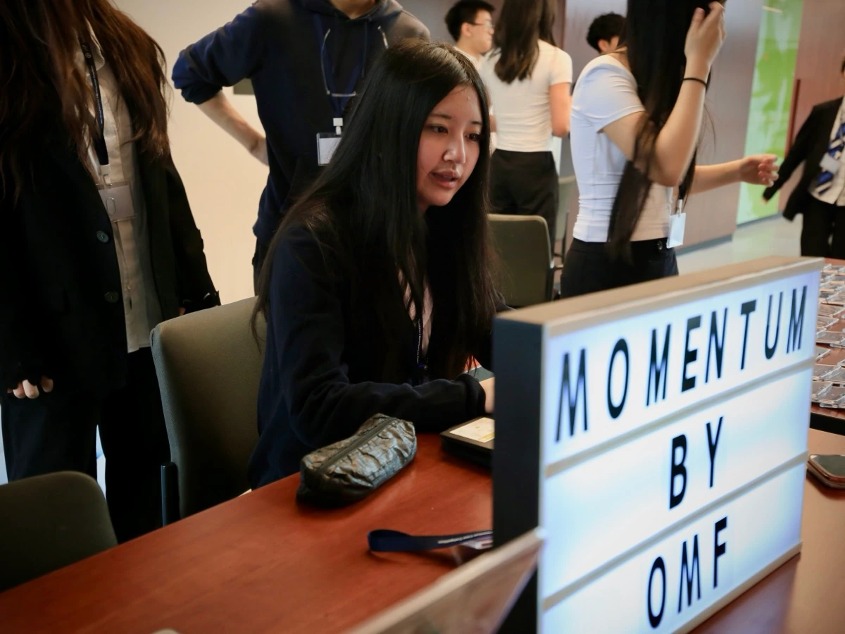 A student welcoming participants at the Momentum registration desk